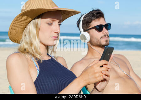 couple listening to music in headphones on mobile phone Stock Photo