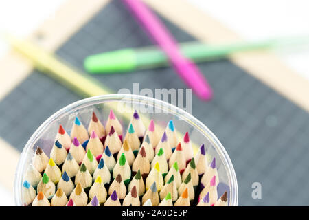 Closeup of multicolored crayon tips  with slate and pens on background Stock Photo