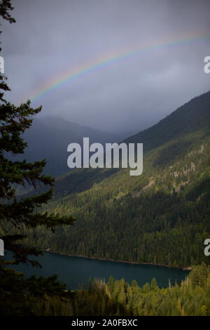 A partial rainbow above the lake and mountains, seen hiking on Goat Lookout trail, at Birkenhead Lake Provincial Park, in summer, BC, Canada Stock Photo
