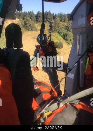 A Coast Guard aircrew aboard an MH-65 Dolphin Helicopter from Air Facility Newport rescued a man stranded on the rocks below “God’s Thumb” north of Lincoln City, Ore., Sept. 2, 2019. The aircrew lowered a rescue swimmer to hoist the man off the cliffs and return him safely to the shore line without any injuries reported. U.S. Coast Guard photos courtesy of Air Facility Newport. Stock Photo