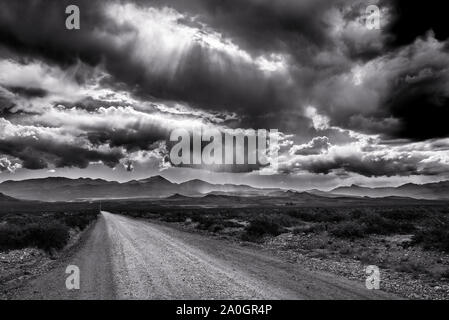 Dusty road and rays of sun through the cluds. taken in Mendoza Province, Argentina Stock Photo