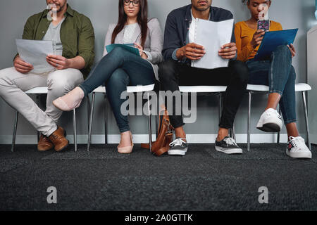 Diverse candidates sitting in queue with their cv at office expecting their turn for interview - young and multiethnic group  Stock Photo
