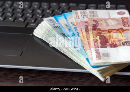 Wages in Russia. Russian paper currency lay on laptop keyboard folded like a fan. Different denominations banknotes. Stock Photo