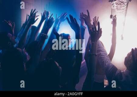 Cheering live shine show performance concept. Crowd shadow of people at during a concert dancing in party club with neon lights raised hands up backgr Stock Photo