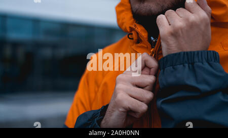 A man fastens his work uniform. Orange worker uniform - hands close up Stock Photo