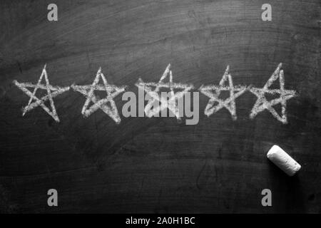 Line of five stars hand drawn on a blackboard with a piece of white chalk below in a concept of rating or ranking for excellence Stock Photo