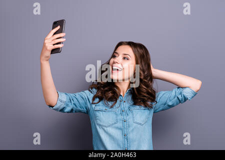 Stylish trendy funny flirty nice cute cheerful adorable lovely attractive magnificent brunette girl with wavy hair in casual denim shirt, taking cool Stock Photo