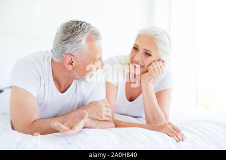 Profile side view photo of carefree, cute, sweet, gorgeous gray hair people, lie on the sofa and look at eyes to each other and speak, recreation in b Stock Photo