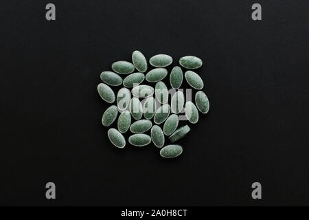 Chlorophyll tablets on black dark background. Flat lay. Dietary supplements. Health support and treatment. Biologically active additives. Detox pills Stock Photo