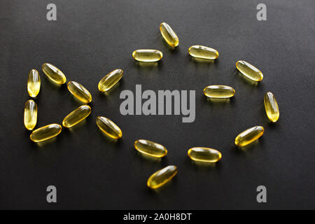 Omega 3 concept. Omega capsules in fish shape on black dark background. Fish oil  pills.  Dietary supplements. Health support and treatment. Biologica Stock Photo