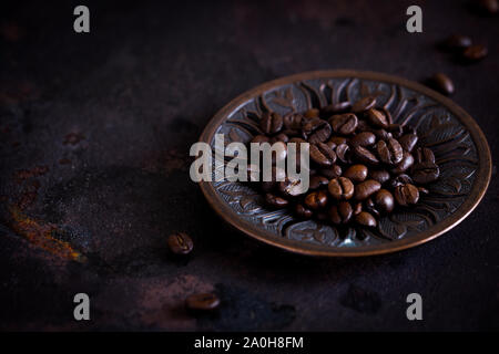 fresh roasted coffee beans on a beautiful plate on a rough rusty background. selective focus, copy space/