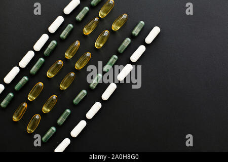 Dietary supplements. Omega 3, spirulina, chlorophyll,magnesium  capsules on black dark background, flat lay. Vitamin pills. Health support and treatme Stock Photo