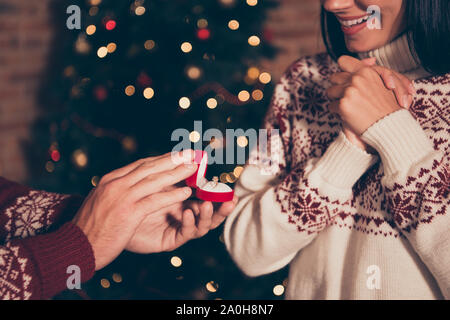 Anniversary, bride and groom concept. Cropped close up photo of glad woman in ornament sweater looking on box with wedding ring  stand in living room Stock Photo