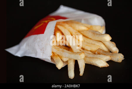 Bag of french fries from McDonalds Restaurant isolated on a black background. Copenhagen, Denmark - September 18, 2019. Stock Photo