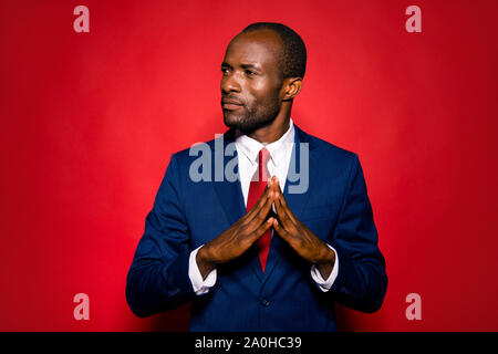 Portrait of nice content focused handsome mulatto rich man company founder wearing blue suit folded hands looking aside isolated over bright vivid red Stock Photo