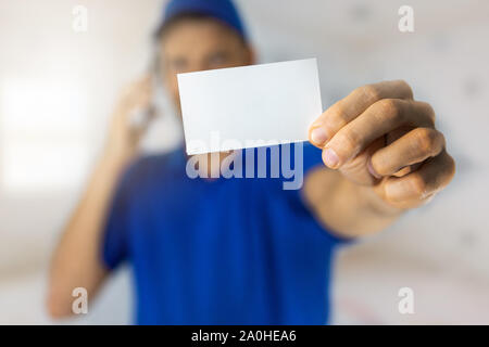 handyman services - worker showing blank business card and making a phone call Stock Photo
