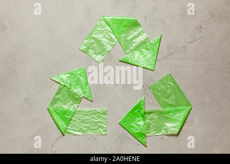 Sign recycling plastic from green bags on gray background. Environmental pollution by disposable bags, recycling. Stock Photo