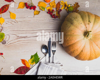 Autumn table setting, background from fallen leaves,apple.physalis, berries with vintage place setting on wooden table. Thanksgiving day concept Stock Photo