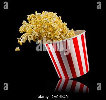 Flying popcorn from striped bucket isolated on black background Stock Photo