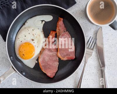 Freshly cooked bacon and eggs with a cup of coffee taken from above against a white table Stock Photo