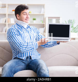 The man freelancer in a cervical collar neck brace working from home Stock Photo