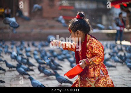 Little girl dressed as Kumari God feeding the pigeons at Kathmandu Durbar Square during Indra Jatra Festival Stock Photo