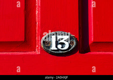 House number 13 on a bright red wooden front door Stock Photo