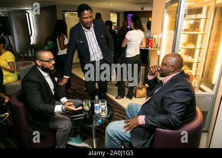 Johannesburg, South Africa - December 10 2014: Young African Men drinking Whiskey out of a tumbler glass in a cigar lounge Stock Photo
