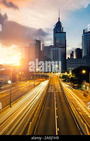 Light trails of traffic in Hong Kong at sunset time with Hong Kong bussines center in background. Asia. Asian tourism, modern city life, or business f Stock Photo