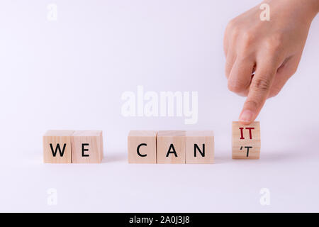 Woman hand flip wooden cube '   'T' form ' WE CAN'T ' to ' WE CAN IT ' Motivation concept. Stock Photo