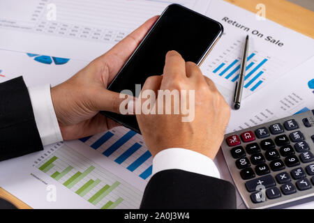Businessman using smart phone over the desk with document paper background. Copy space for advertisers. Business concept or Online business concept. Stock Photo