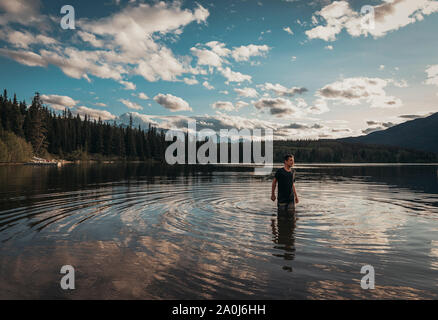 Teenage boy standing in a lake in the Rocky Mountains. Stock Photo