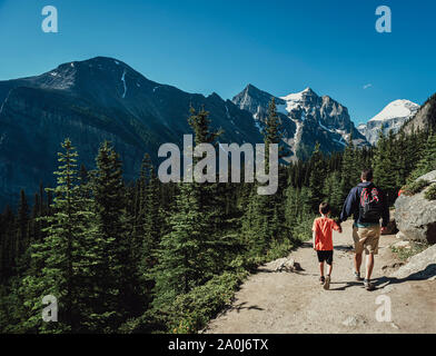 Father and son holding hands hiking on a path in the mountains. Stock Photo