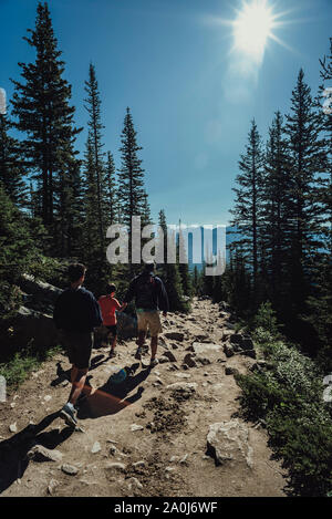 Father and sons hiking down a rocky path in the mountains together. Stock Photo