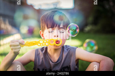 Young boy blowing bubbles outdoors on a summer day. Stock Photo