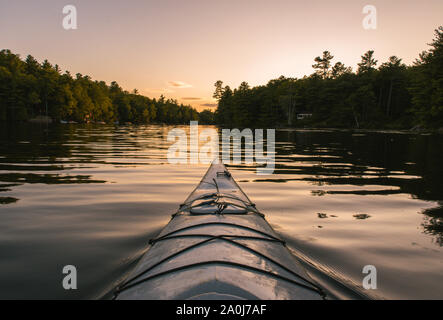 Kayaking on calm water at sunset from point of view of paddler. Stock Photo
