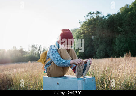 young school boy holding his shoes whilst walking home at sunset Stock Photo