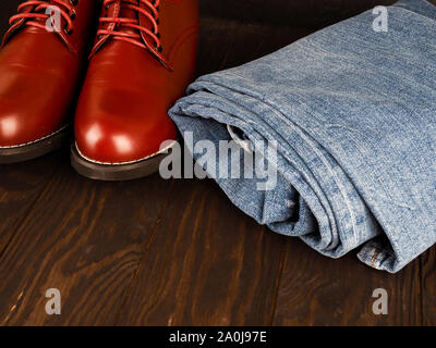 Fashionable concept. casual wear, yellow work boots from natural leather, blue jeans on black background. Trendy casual shoes clothes. Stock Photo