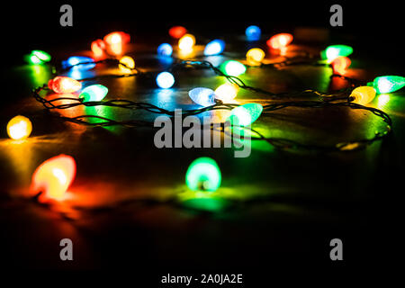 Christmas tree branch and lights on wooden background. View with copy space. Colored lights on a Christmas garland in the dark of night Stock Photo