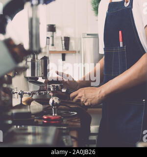 Man barista using coffee machine for making coffee in the cafe, Vintage color tone. Stock Photo