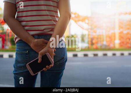 Unrecognizable woman in comfortable clothes is looking at the decoration lantern and holding a mobile phone behind. Stock Photo