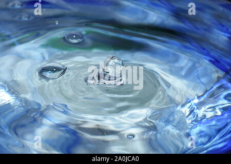 Splash and ripples in blue water liquid Stock Photo