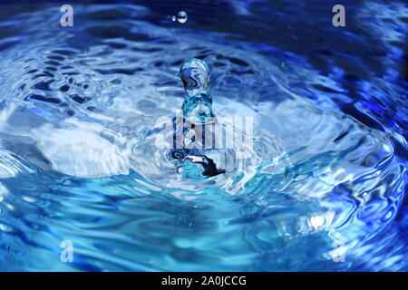 Splash and ripples in blue water liquid Stock Photo