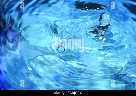 Splash and ripples in blue water liquid Stock Photo
