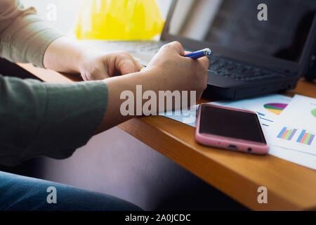 Hands of architect holding a pen and working on office desk, Business concept. Stock Photo