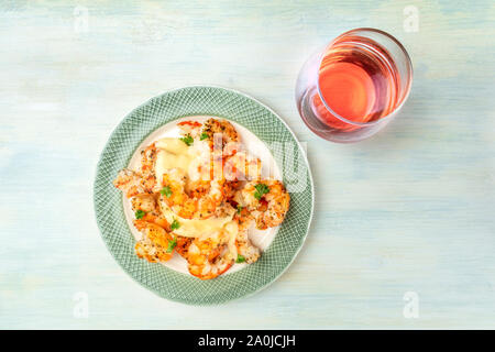 Fired shrimps with fresh parsley leaves, with a dressing, a glass of rose wine, and a place for text Stock Photo