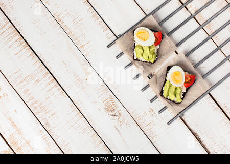 Two diet sandwiches with avocado, tomato, cream cheese on white wooden background. Food for vegetarians. Space for your text. Flat lay, top view. Stock Photo