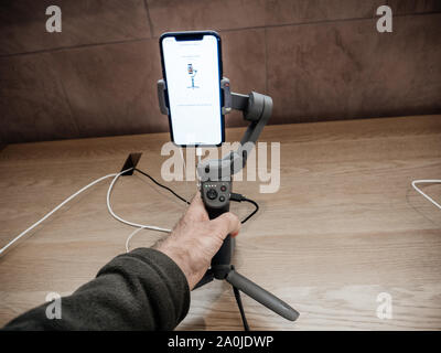 Paris, France - Sep 20, 2019: Man hand holding DJI Osmo 3 gimbal with the new iPhone 11, 11 Pro and Pro Max are displayed in Apple Store Stock Photo
