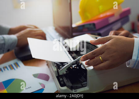 Colleagues working together with typing typewriter and laptop on office desk, Business and Office life concept. Stock Photo