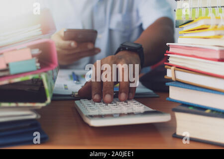 Man is using calculator and working with stack of documents on office desk, Businessman is analyzing marketing with statistics chart, Business and Off Stock Photo
